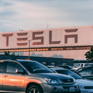 Tesla factory with parked cars during sunset, showcasing modern automotive industry vibes.